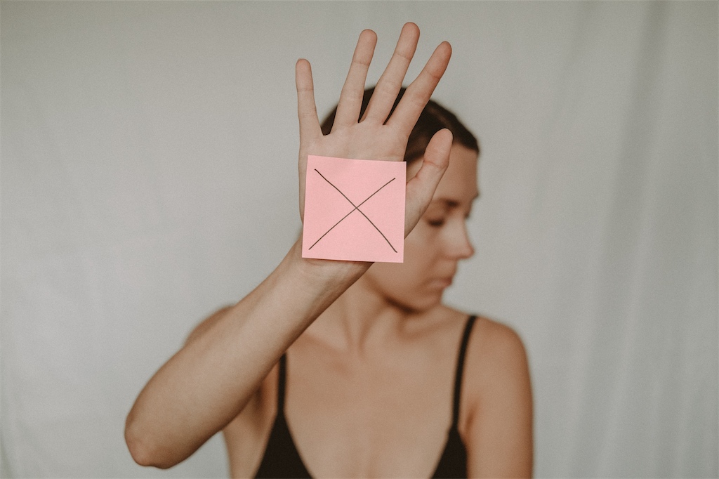 woman with a sticky note with an "X" on it